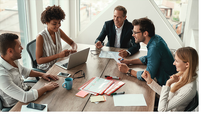 Stock image Group of young business people discussing something and smiling while sitting at the office table