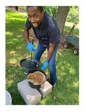 SFA student, Ajani Brown, cooking bread with a Dutch Oven